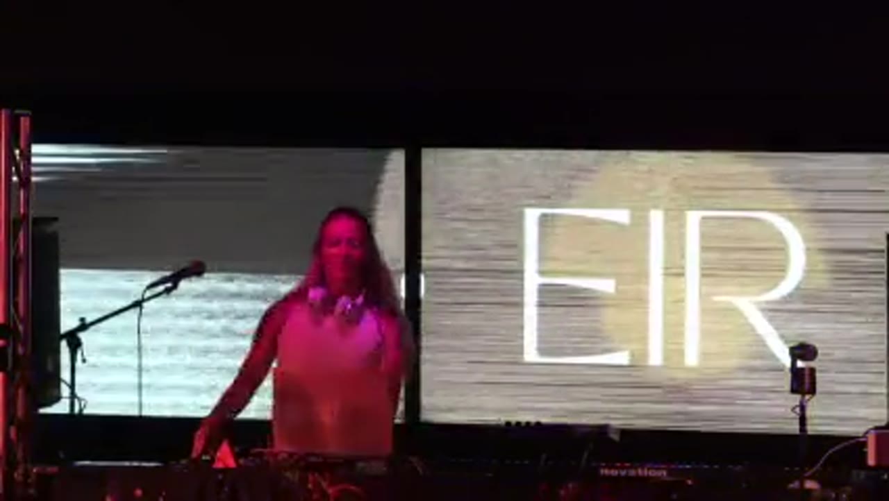 EIR at the decks under pink light, her name filling the LED wall behind her